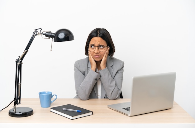 Young business mixed race woman working at office frustrated and covering ears