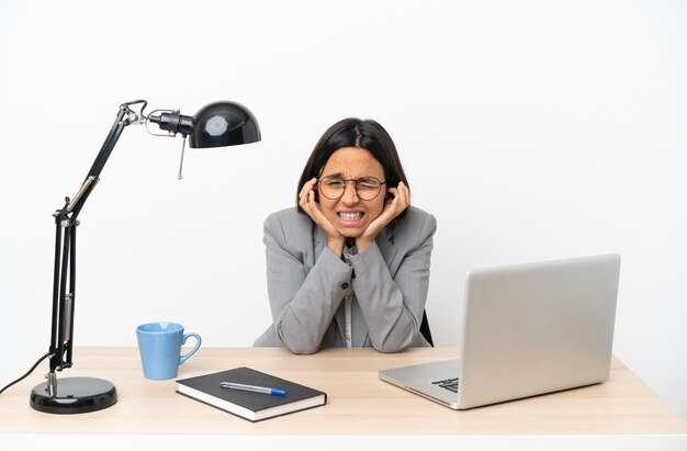 Young business mixed race woman working at office frustrated and covering ears