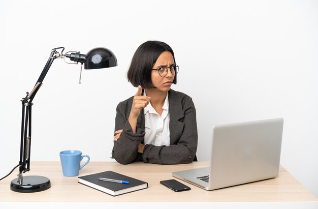 Young business mixed race woman working at office frustrated and pointing to the front