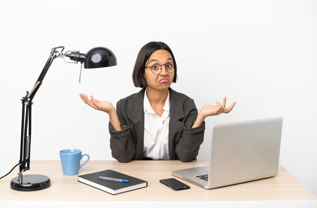 Young business mixed race woman working at office making doubts gesture