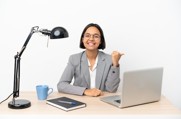 Young business mixed race woman working at office pointing to the side to present a product