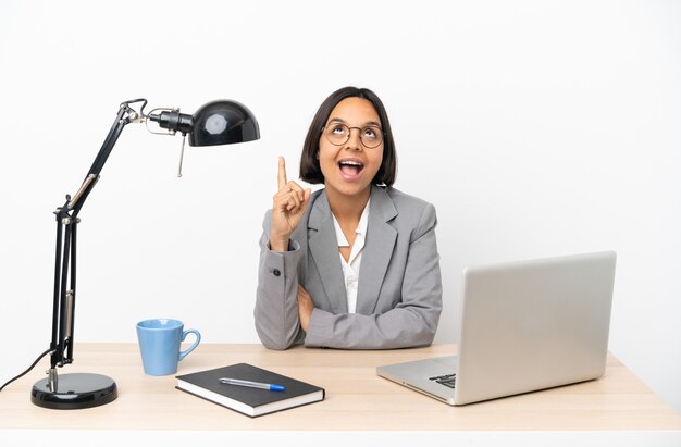 Young business mixed race woman working at office pointing up and surprised