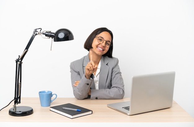 Young business mixed race woman working at office showing and lifting a finger