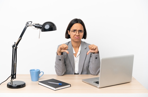 Young business mixed race woman working at office showing thumb down with two hands