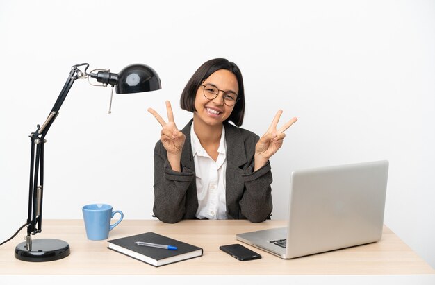 Young business mixed race woman working at office showing victory sign with both hands