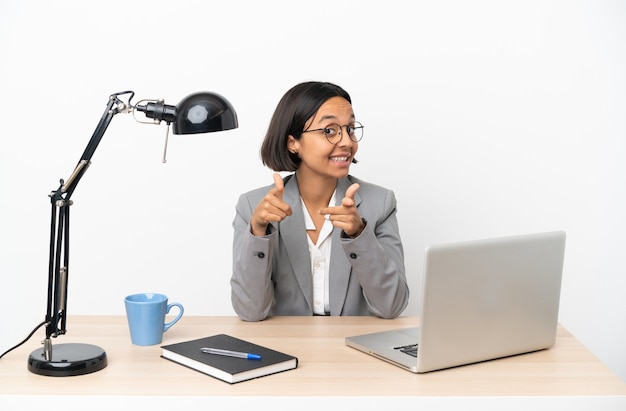 Young business mixed race woman working at office surprised and pointing front