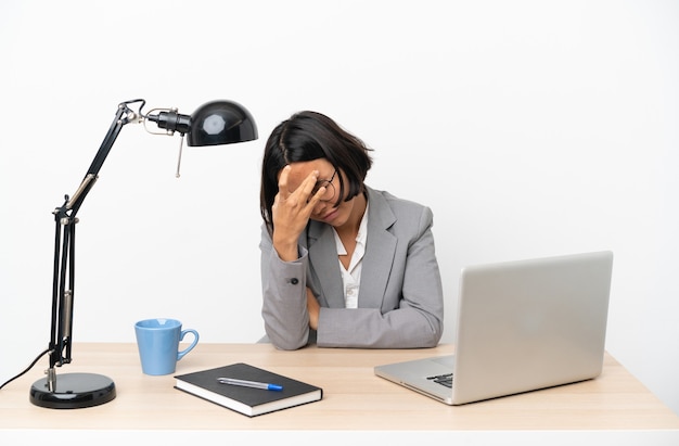 Молодая деловая женщина смешанной расы, работающая в офисе с головной болью