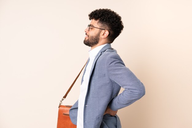 Young business Moroccan man isolated on beige background suffering from backache for having made an effort