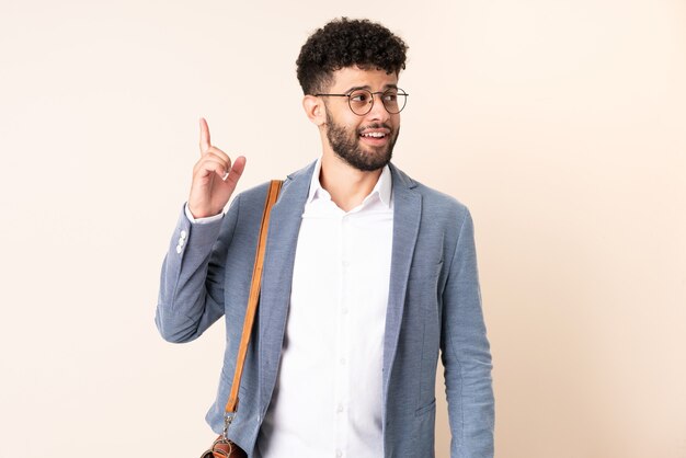 Young business Moroccan man isolated on beige intending to realizes the solution while lifting a finger up