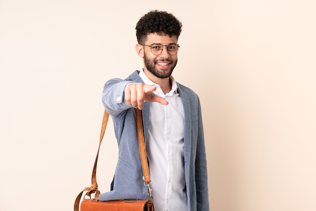 Young business Moroccan man isolated on beige wall points finger at you with a confident expression