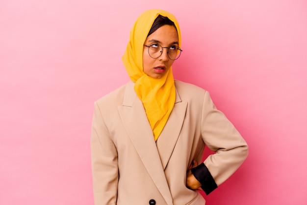 Young business muslim woman isolated on pink wall tired of a repetitive task