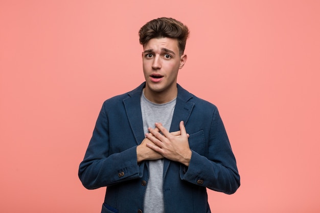 Young business natural man has friendly expression, pressing palm to chest