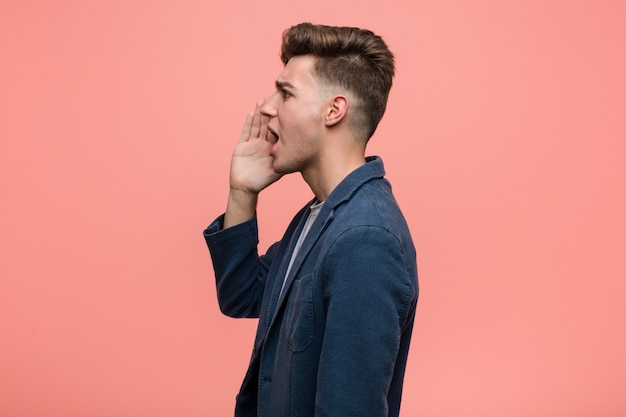 Young business natural man shouting and holding palm near opened mouth.