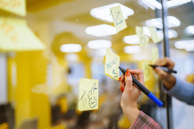 Young business people discussing and planning strategy front of glass wall marker and stickers