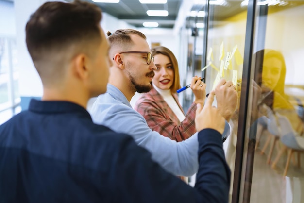 Young business people discussing and planning strategy Front of glass wall marker and stickers