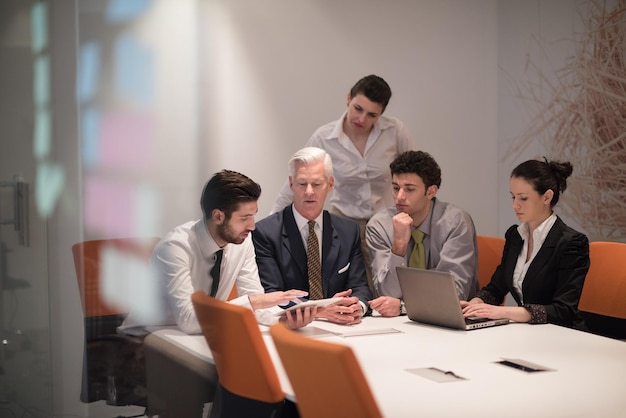 젊은 사업가들은 현대 창업 사무실에서 고위 관리자와 회의를 합니다. 팀 리더는 태블릿과 노트북 컴퓨터에서 프레젠테이션과 결과를 찾고 있습니다.