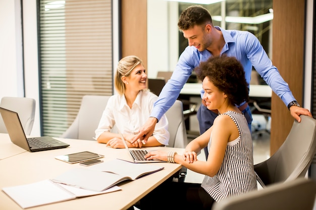 Молодые люди бизнеса, используя ноутбук и улыбается во время работы в офисе
