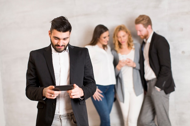 Young business people with mobile phone standing by the wall