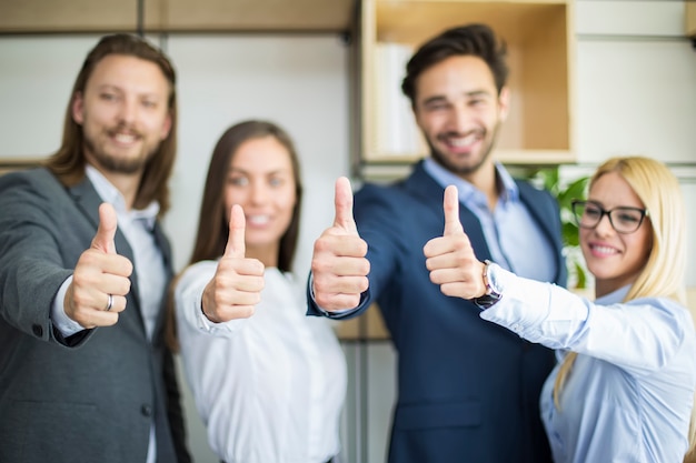 Young business people with thumb up standing in the office