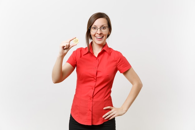 빨간 셔츠를 입은 젊은 비즈니스 교사 여성, 비트코인을 들고 있는 안경, 흰색 배경에 격리된 황금색 금속 동전. 미래 통화, 교육 성취 경력 재산 개념. 여사장님.