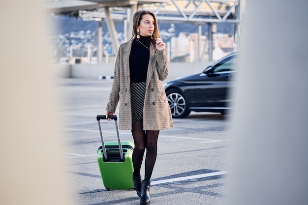 Young business woman against black luxury car