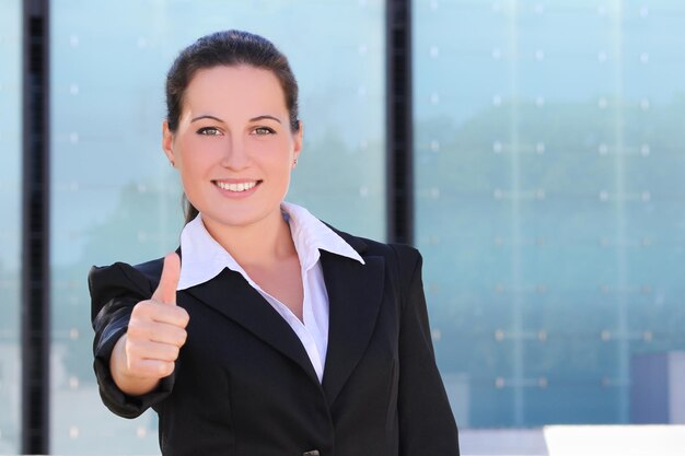Young business woman in black suit thumbs up outside
