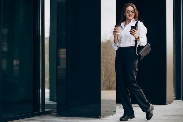 Young business woman drinking coffee by the business center