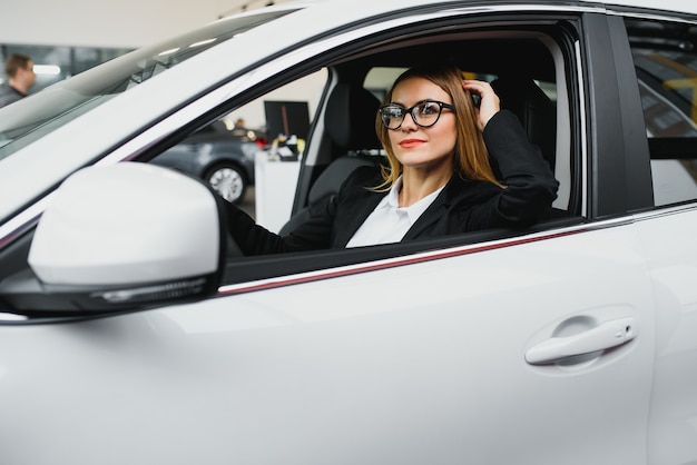 若いビジネス女性が彼女の車を運転して動作します。