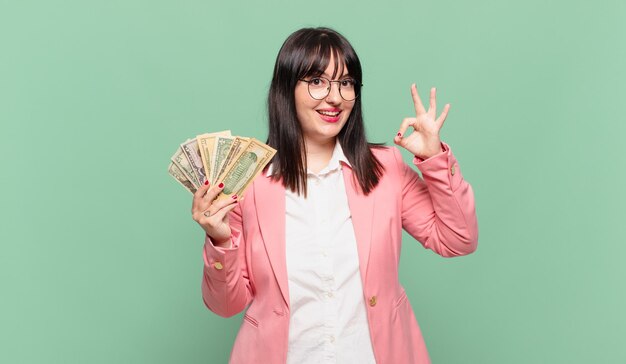 young business woman feeling happy, relaxed and satisfied, showing approval with okay gesture, smiling