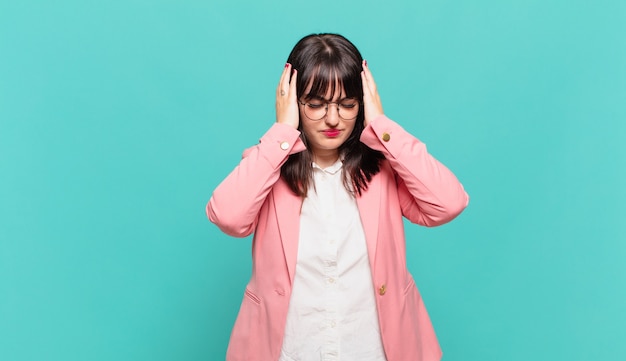 Young business woman feeling stressed and frustrated, raising hands to head, feeling tired, unhappy and with migraine