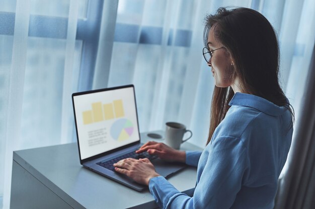 Young business woman freelancer in round glasses using computer