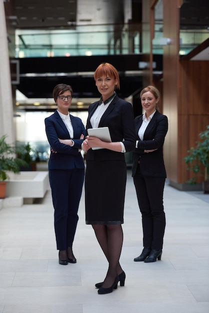 young business woman group,  team standing in modern bright office and working on tablet computer