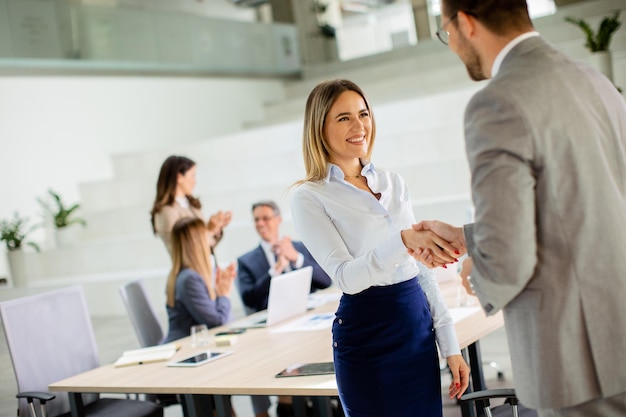 Young business woman handshaking with his colleague in the office