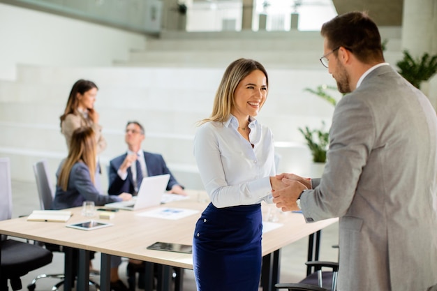 Young business woman handshaking with his colleague in the office