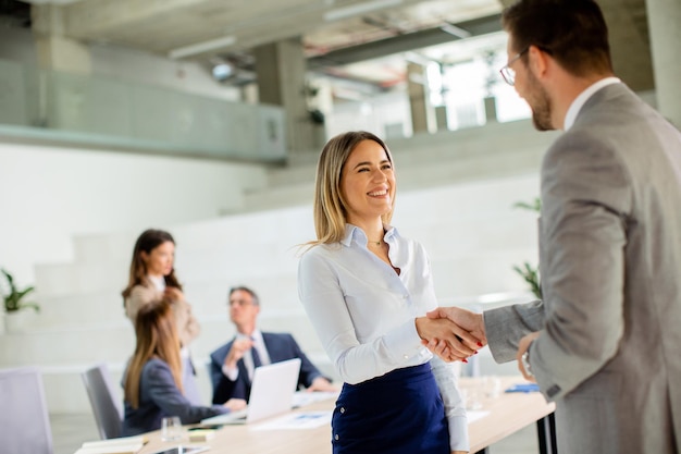 Young business woman handshaking with his colleague in the office
