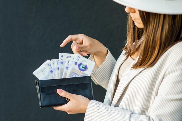 Young business woman holding black wallet with pounds in hands close up of female hands The concept of cash payments savings and salaries