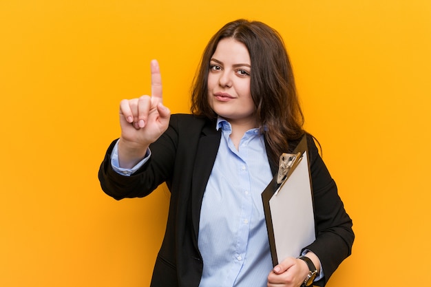 Young  business woman holding a clipboard showing number one with finger.