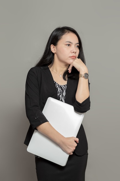 Young business woman holding laptop with dreamy expression