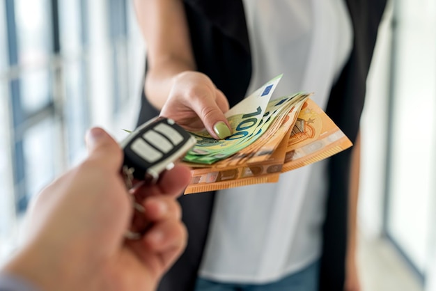 A young business woman is given car keys and she is euros for a car The concept of buying a car Business concept