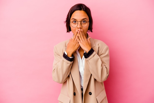 Young business woman isolated on pink wall shocked covering mouth with hands