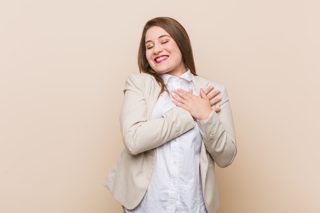 Young business woman laughing keeping hands on heart