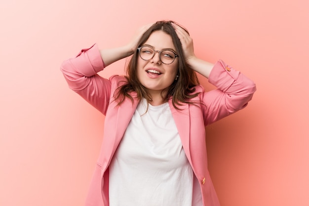 Young business woman laughs joyfully keeping hands on head