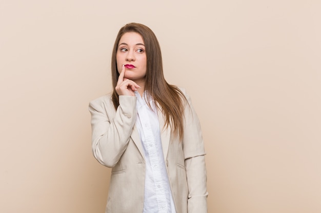 Giovane donna d'affari guardando lateralmente con espressione dubbiosa e scettica.