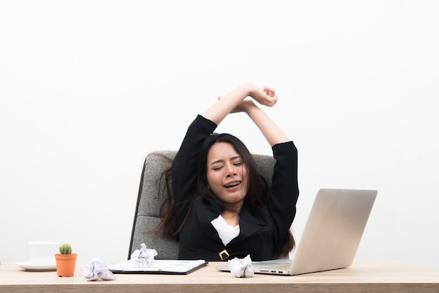 Young business woman looks stressful and tired sitting at workplace with laptop on the table isolated on white background