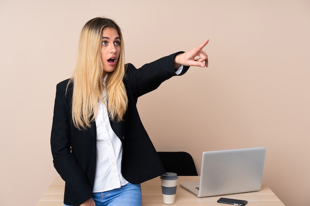 Young business woman in a office pointing away