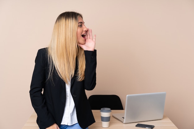 Young business woman in a office shouting with mouth wide open