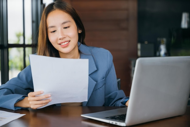 Young business woman reading report document compare with laptop computer