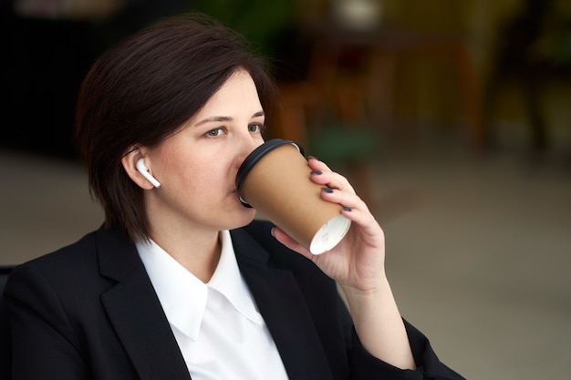 Young business woman relaxing, listening music and drinking coffee during break from work