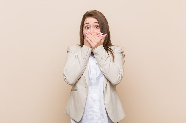 Young business woman shocked covering mouth with hands.