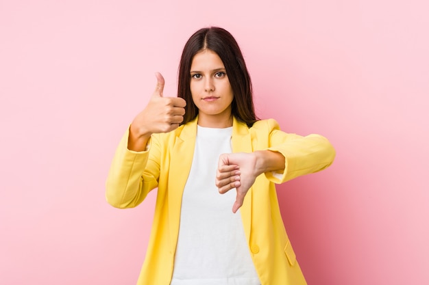 Young business woman showing thumbs up and thumbs down, difficult choose concept